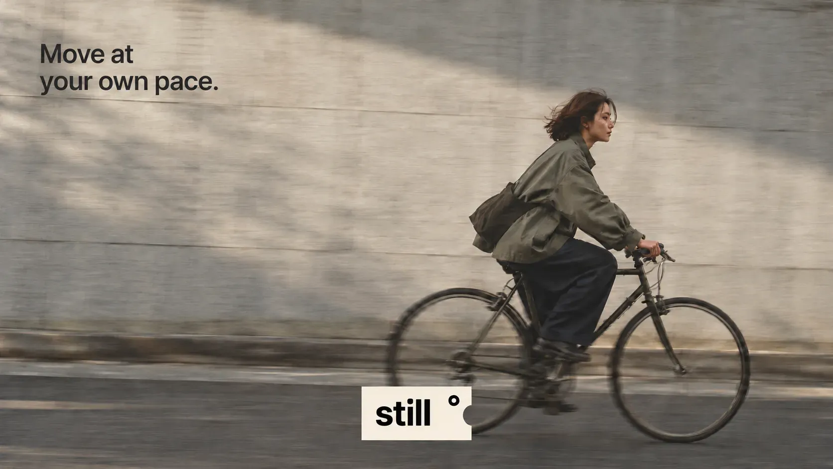Move at your own pace campaign visual with a woman cycling past a sunlit wall