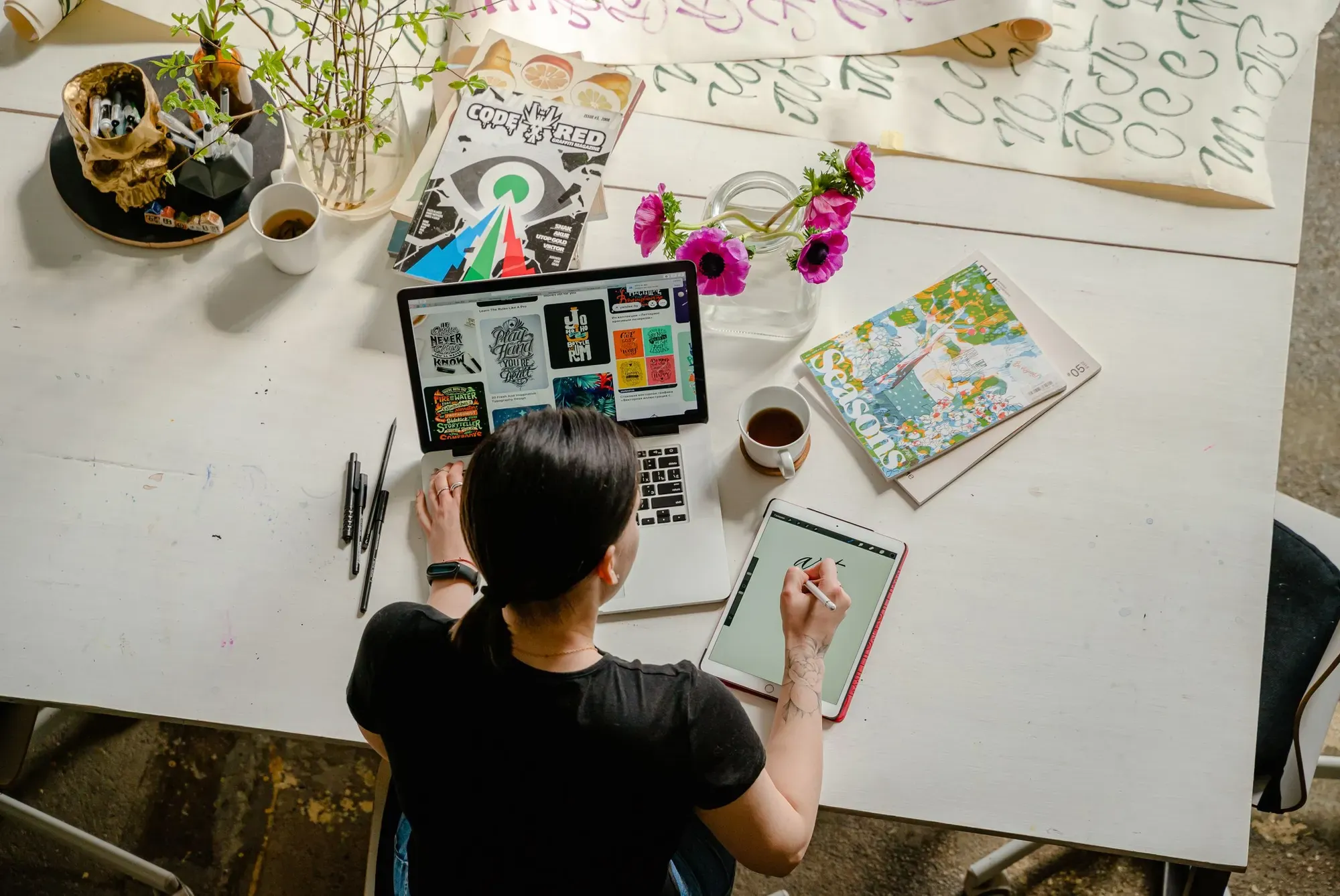 Designer working on a moodboard at a desk covered in references
