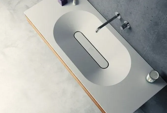 Top view of a pale stone basin with a slim steel tap